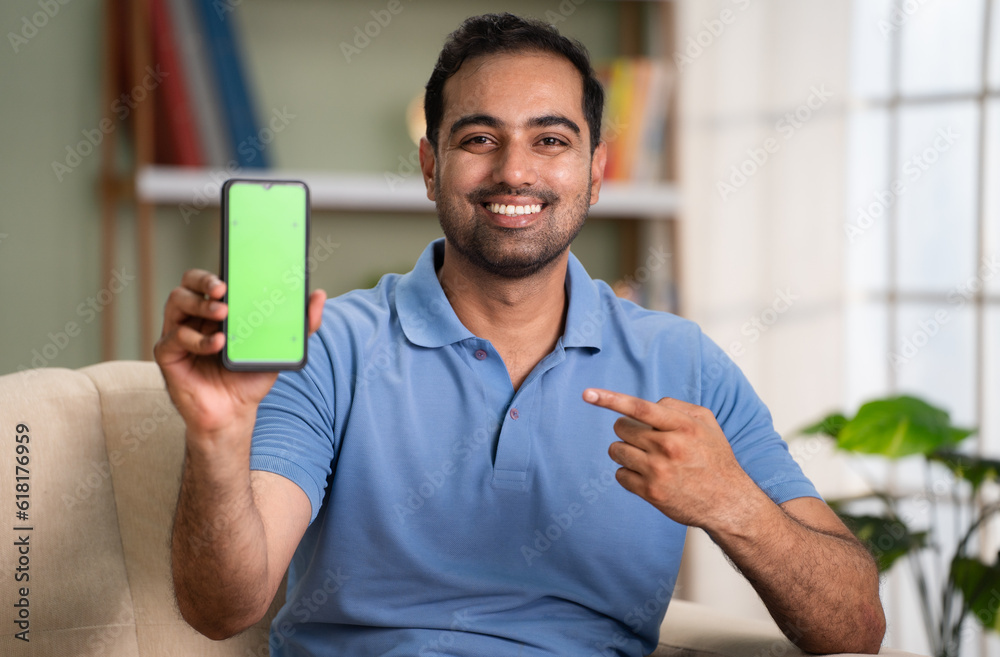 Man Using Mobile App Happy smiling indian man showing green screen mobile phone by pointing ...