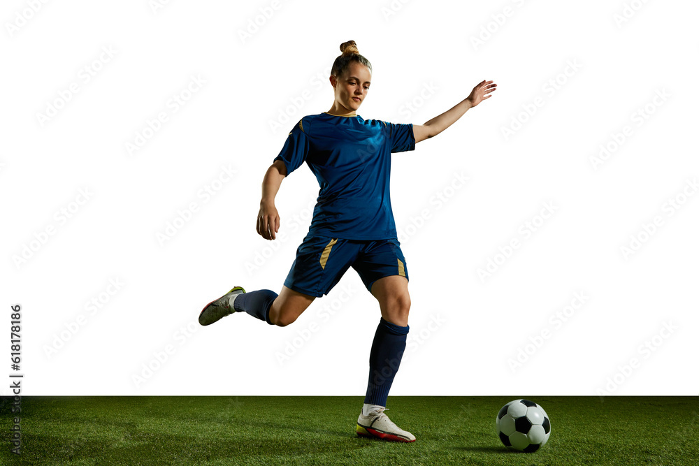 Obraz premium Young sportive girl in blue uniform, football player in motion, training, kicking ball against white background. Concept of professional sport, action, lifestyle, competition, hobby, training, ad