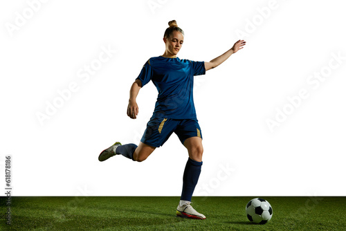 Young sportive girl in blue uniform, football player in motion, training, kicking ball against white background. Concept of professional sport, action, lifestyle, competition, hobby, training, ad © master1305