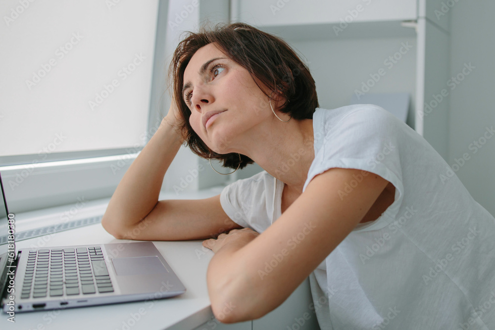 Tired, frustrated, exhausted, stressed woman sitting at desk . Female procrastinate at work. Daylight work. Girl in White tshirt Tired, frustrated, exhausted, stressed woman sitting at desk . Female procrastinate at work. Daylight work. Girl in White tshirt