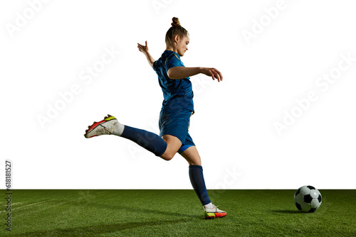 Young sportive girl in blue uniform, football player in motion, training, kicking ball against white background. Concept of professional sport, action, lifestyle, competition, hobby, training, ad