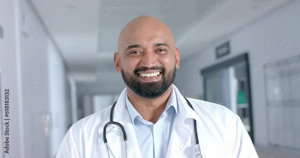 Portrait of happy biracial male doctor wearing lab coat, smiling in corridor, slow motion Portrait of happy biracial male doctor wearing lab coat, smiling in corridor, slow motion