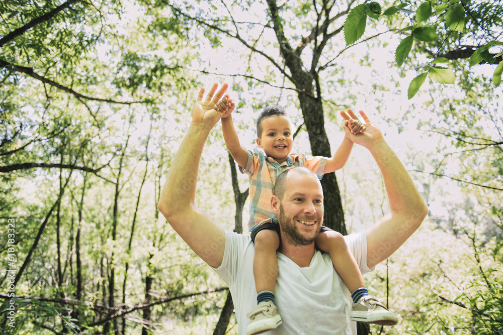 father with her son on his shoulder in the forest.