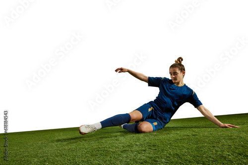 Concentrated female athlete  young girl  football player kicking ball in motion on field grass against white background. Concept of professional sport  action  lifestyle  competition  training  ad