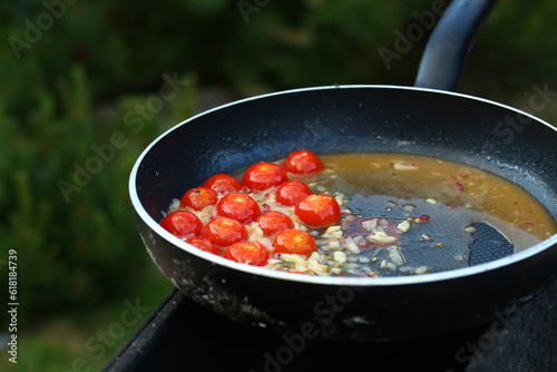roasted cherry tomato with garlic and onion in pan on barbecue coal