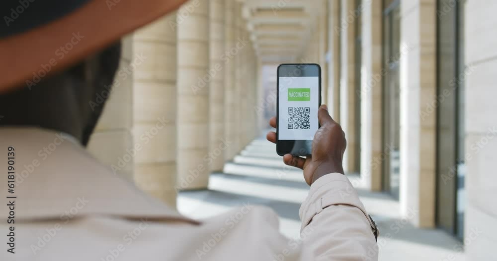 View over shoulder of african man holding smartphone with vaccinated qr-code View over shoulder of african man holding smartphone with vaccinated qr-code