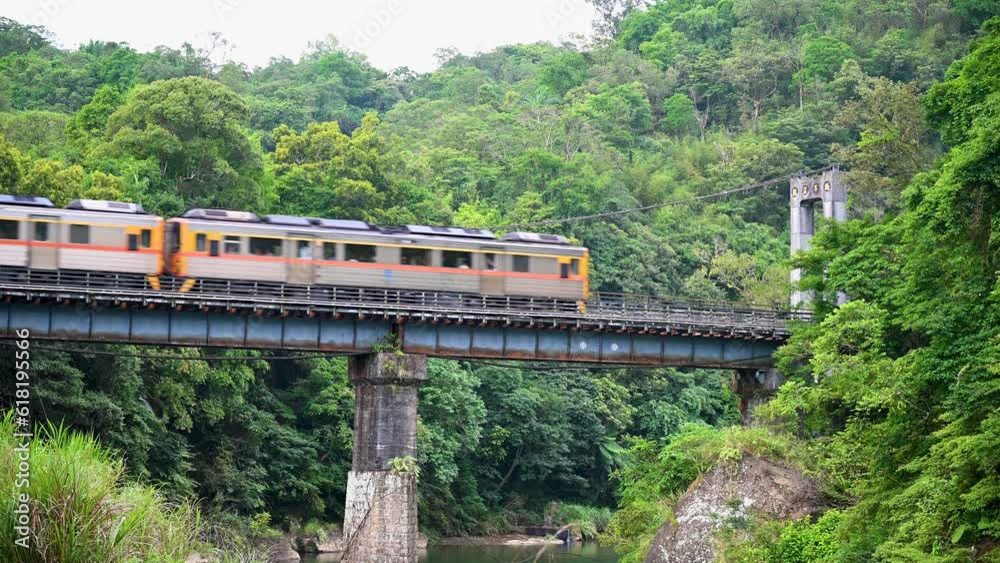 A yellow diesel train passes the bridge over the valley. Along the Pingxi line, there are river valleys, potholes and waterfalls. Taiwan A yellow diesel train passes the bridge over the valley. Along the Pingxi line, there are river valleys, potholes and waterfalls. Taiwan