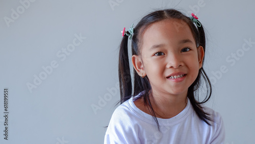 Little Asian girl smiling to the camera. The girl wearing casual white with pigtails