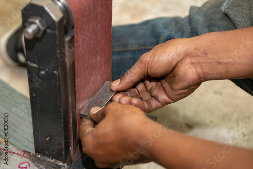 The manual hand grinding process on sandpaper belt machine.
