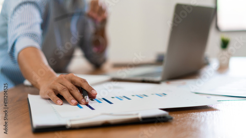 Close up hands of businesswoman reading financial business document and working on laptop in office