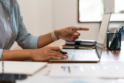 Close up hands of businesswoman is pointing on screen to reading data and typing on laptop keyboard