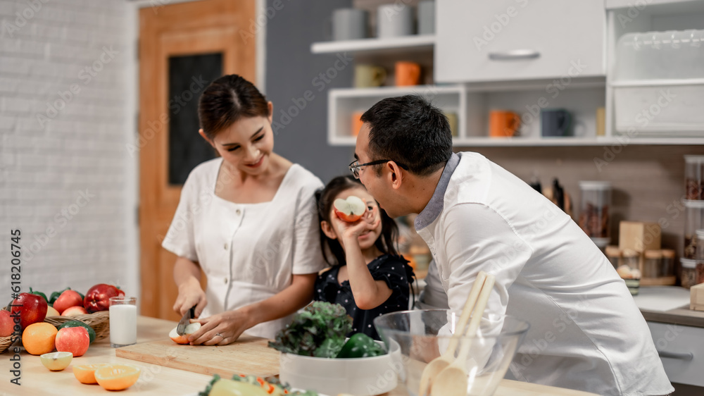 The family members happily and playfully prepare a bowl of various types of fruity and vegetable salad. Making quirky faces, joking, laughing, smiling, can create a good mood and positive atmosphere. The family members happily and playfully prepare a bowl of various types of fruity and vegetable salad. Making quirky faces, joking, laughing, smiling, can create a good mood and positive atmosphere.