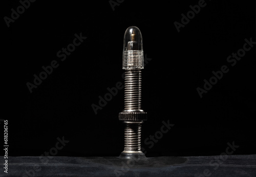 The nipple of a bicycle camera on a black, macro