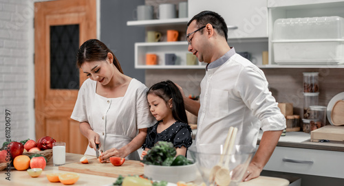 The family members happily and playfully prepare a bowl of various types of fruity and vegetable salad. Making quirky faces, joking, laughing, smiling, can create a good mood and positive atmosphere.