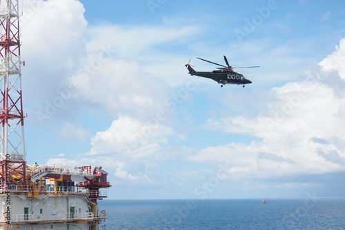 Helicopter Landing Officer communicating with pilot and copilot for service on ground and support as the pilot required. The helicopter landing on the deck in oil and gas platform