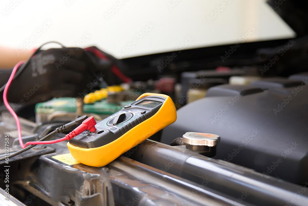 A technician is checking the car battery for availability. A technician is checking the car battery for availability.