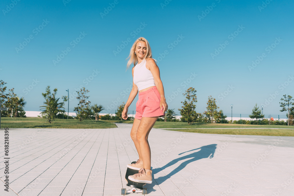 Beautiful stylish woman surf on a longboard on a hot summer day. Summer hobbies and sports.