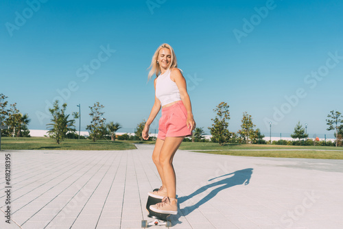 Beautiful stylish woman surf on a longboard on a hot summer day. Summer hobbies and sports.