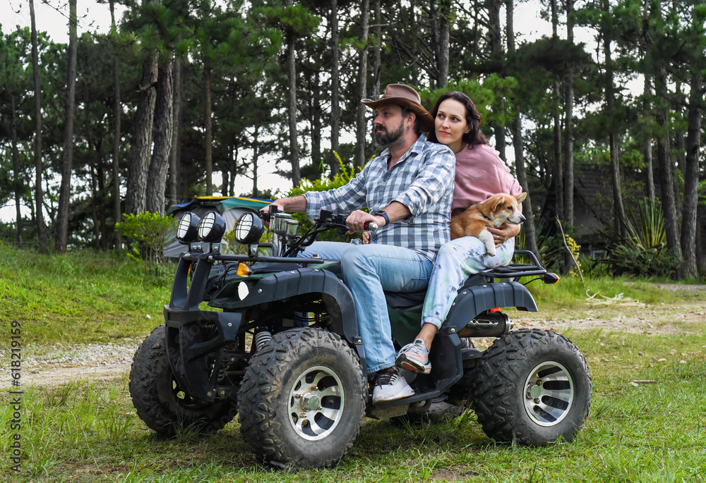 Portrait of young married couple sitting on a quad bike in the forest Portrait of young married couple sitting on a quad bike in the forest