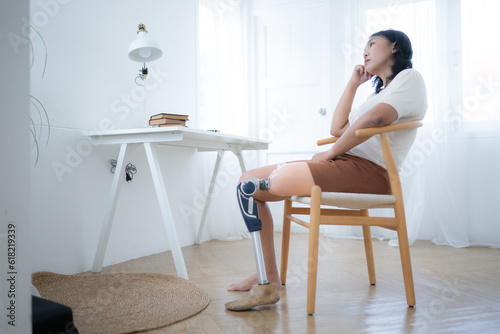 Asian woman with prosthetic leg sitting on chair in the living room photo