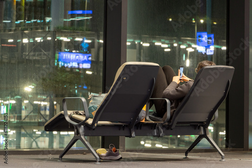 A young woman with a mobile phone makes selfie photos when rest at night airport hall