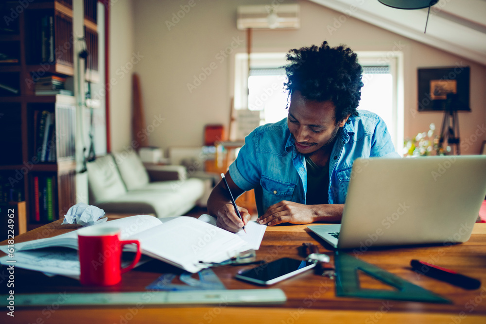 Young man of african ethnicity studying and using the laptop at home Young man of african ethnicity studying and using the laptop at home