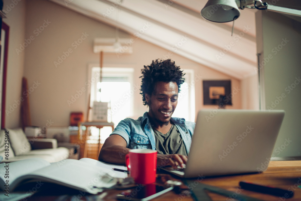 Young man of african ethnicity studying and using the laptop at home Young man of african ethnicity studying and using the laptop at home