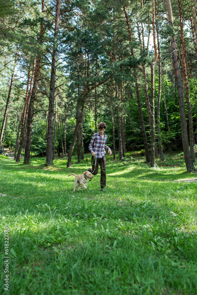 Teenage boy with dog runs in forest. Outdoor running. Pet concept. Teenage boy with dog runs in forest. Outdoor running. Pet concept.