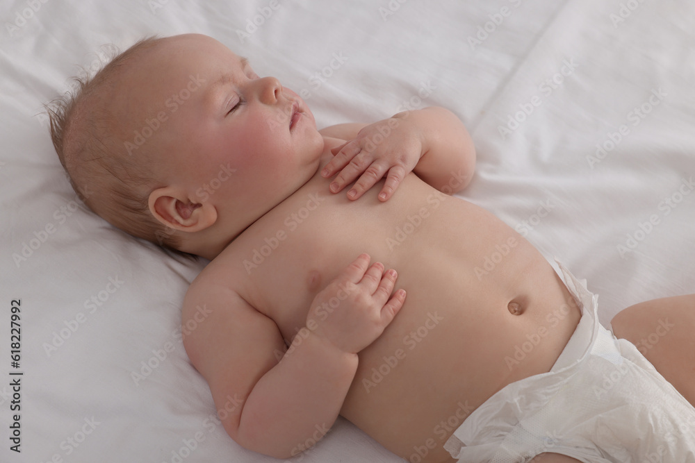 Cute newborn baby in diaper sleeping on bed at home