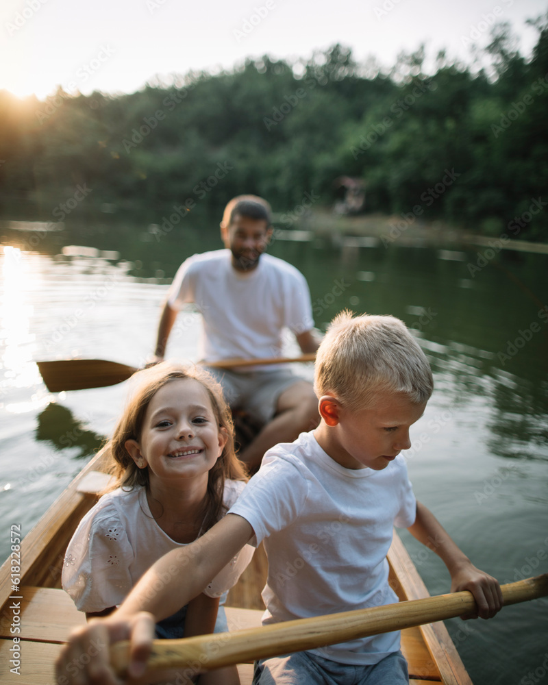 Brother and sister learning to paddle canoe with father Brother and sister learning to paddle canoe with father