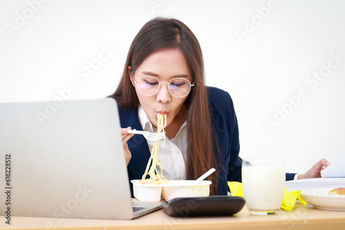 Portrait of a beautiful girl  an employee or an executive in an office wearing a blue suit  eating at a desk. business concept