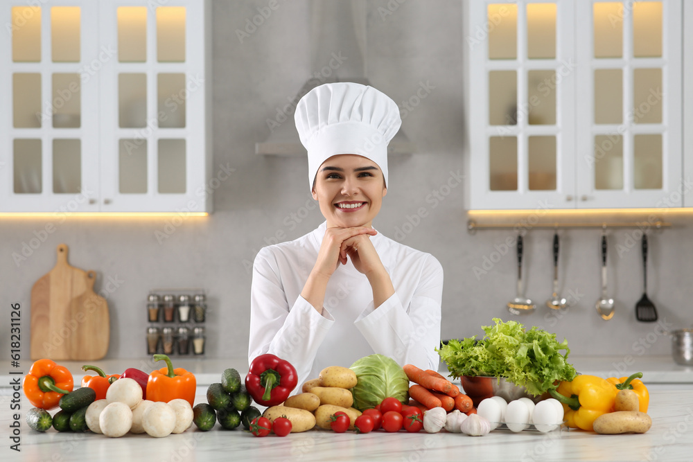 Portrait of happy chef near fresh vegetables at white marble table in kitchen Portrait of happy chef near fresh vegetables at white marble table in kitchen