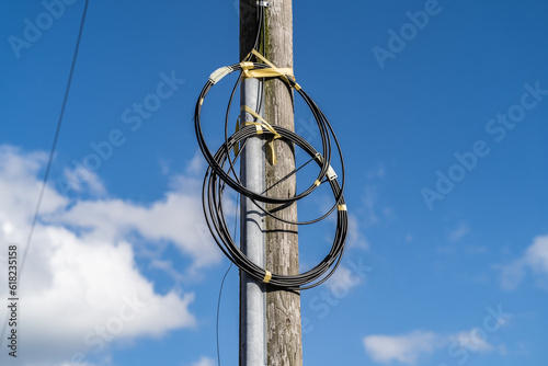 Fibre optic cables on telegraph pole against blue sky with clouds background, telecommunication and infrastructure editorial illustration.