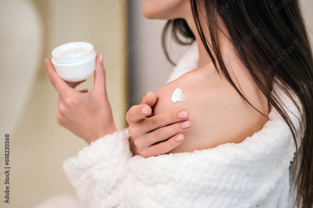 female applying moisturizing cream at her shoulder female applying moisturizing cream at her shoulder