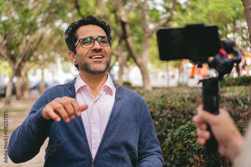 middle-aged Latin man businessman, influencer creating social media content, being filmed with a mobile phone on a gimbal