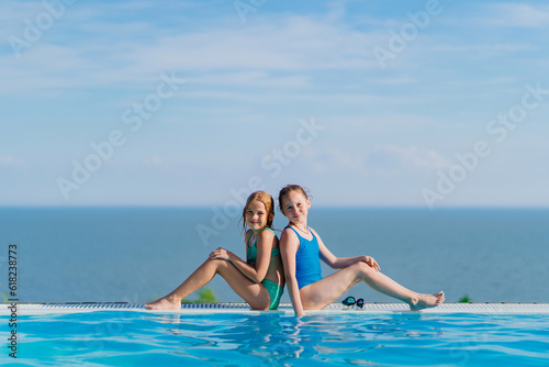 Two teenage girls sitting on the side of the pool