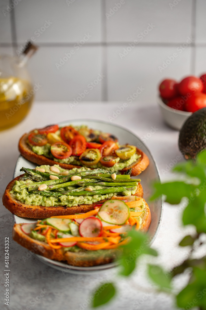 Toasted sourdough bread with grilled asparagus, avocado, tomatoes, radish and herbs for single serving. Avocado toast. Breakfast idea. Healthy food concept. Toasted sourdough bread with grilled asparagus, avocado, tomatoes, radish and herbs for single serving. Avocado toast. Breakfast idea. Healthy food concept.