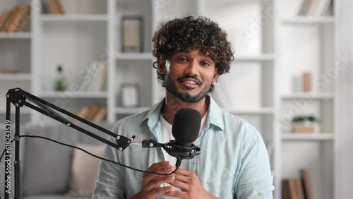 Microphone, podcast and Indian man speaker in his living room. Creative streamer, internet influencer or online content creator live streaming for audience. Camera view.