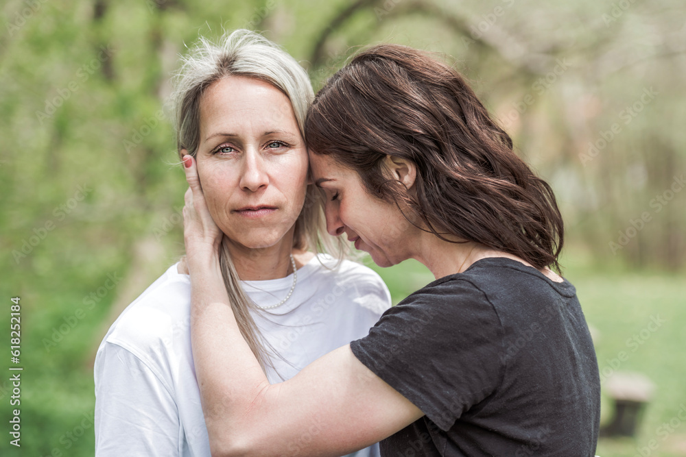 woman comforting her sad friend who is complaining in the park woman comforting her sad friend who is complaining in the park
