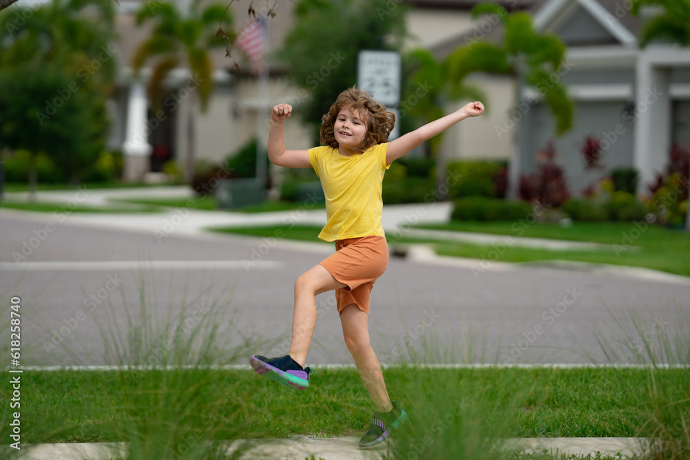 Cute kid boy running across american neighborhood street. Summer, childhood, leisure and people concept. Happy little blonde child boy running in summer park outdoor. Sport and run.