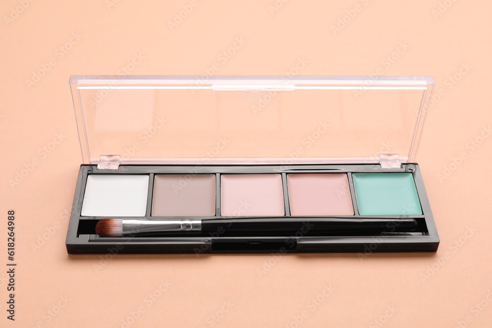 Colorful contouring palette with brush on beige background, closeup. Professional cosmetic product Colorful contouring palette with brush on beige background, closeup. Professional cosmetic product