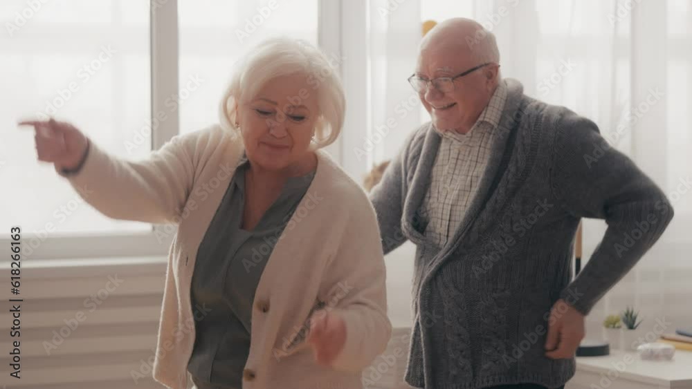 Funny senior couple actively dancing and laughing, enjoying pastime at home Funny senior couple actively dancing and laughing, enjoying pastime at home