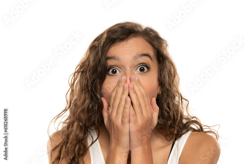 Shocked young woman covering mouth with hands isolated on white background