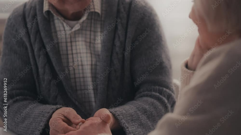 Man in his 60s putting engagement ring on girlfriend's finger, making proposal Man in his 60s putting engagement ring on girlfriend's finger, making proposal