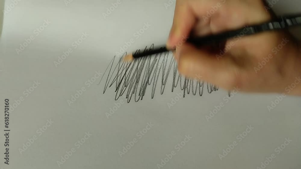 Un primer plano de una mano con un lápiz de madera dibujando  en una hoja de color blanco.