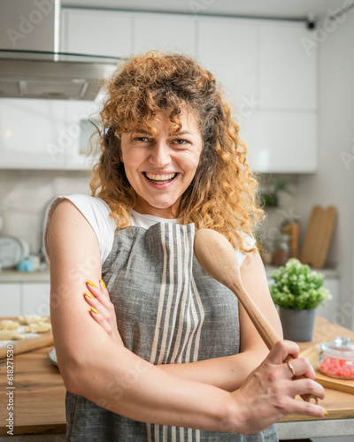 One happy young adult caucasian woman wear apron in the kitchen smile