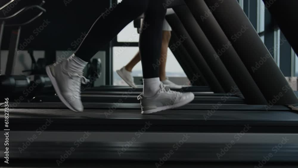 Sporty people jogging on treadmill unknown sportswoman female runner legs feet in sneakers run on sport machine in fitness gym cardio exercise jog fast interval running pace workout healthy lifestyle