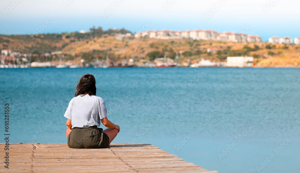 Woman relaxing meditating on the pier by the sea, enjoying her day. Woman relaxing meditating on the pier by the sea, enjoying her day.