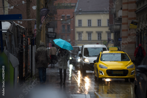 Rain in a city, cars and person with umbrella