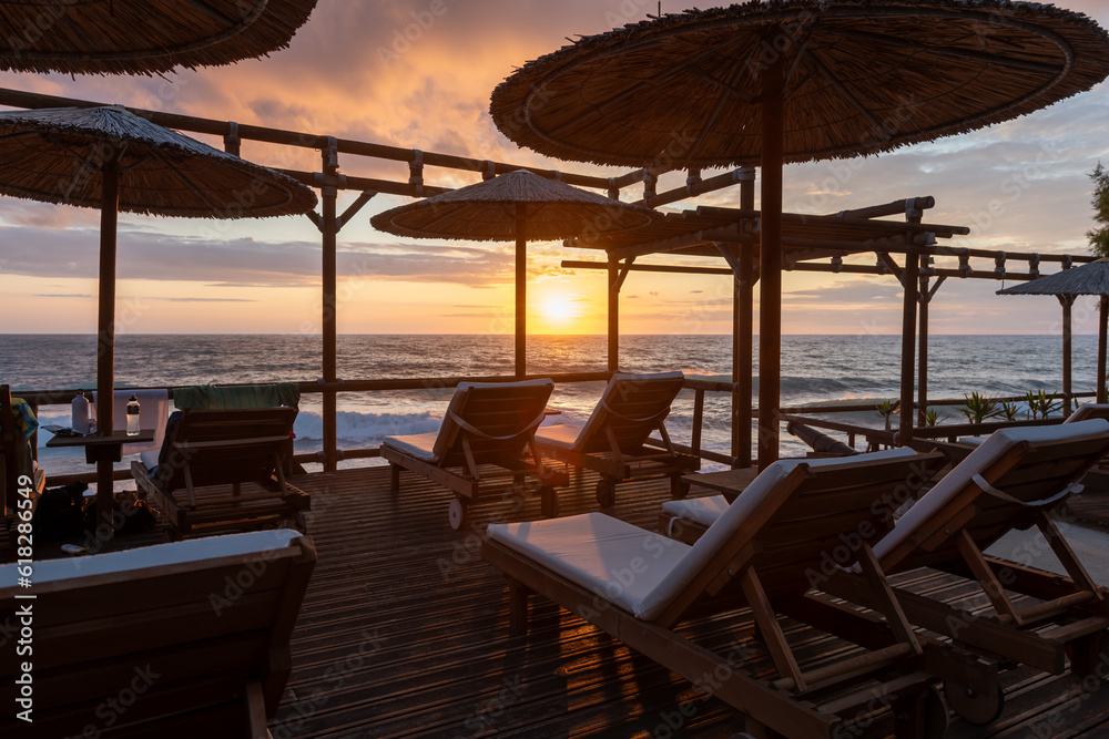 A tourist facility with sun beds and umbrellas by the sea with a spectacular sunset view.